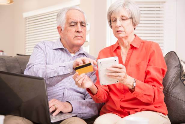 Man and woman sitting on couch using a calculator to see the amount left on their gift card.