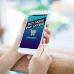 Woman holding a smartphone with a Buy Now Pay Later written on screen.