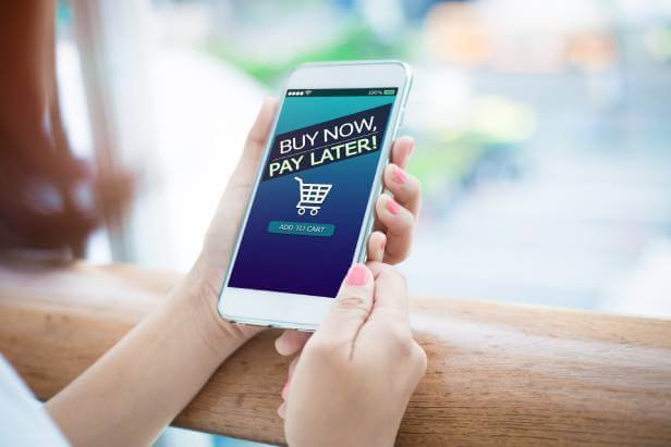 Woman holding a smartphone with a Buy Now Pay Later written on screen.