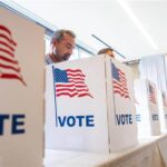 U.S. election booths containing voters at a voting center.